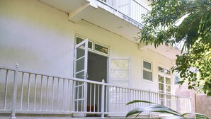 A two-story building with a balcony, a concrete foundation, and a window with an open door. - Eco Bless Inn (Kandy)