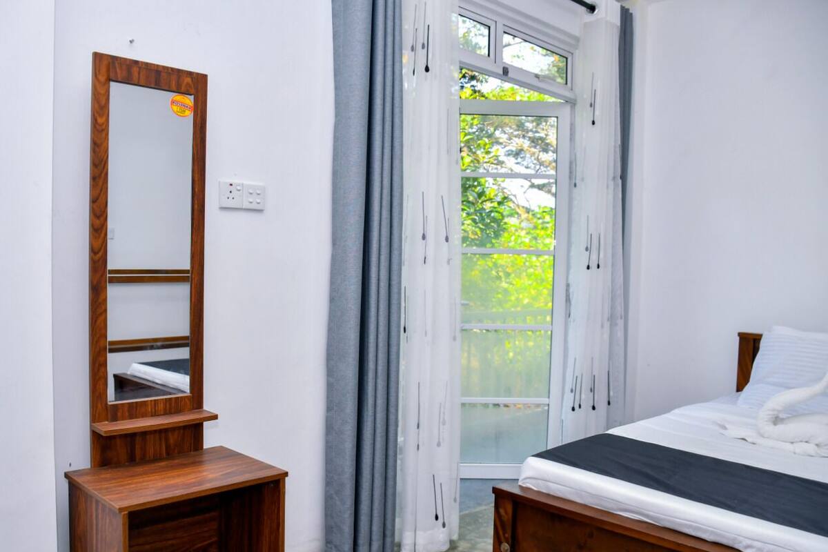 Un dormitorio con una cama de madera, una mesita de noche, un espejo y una ventana con cortinas.