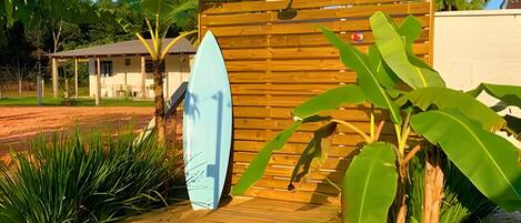 A wooden gate with two surfboards leaning against it, surrounded by tropical plants.