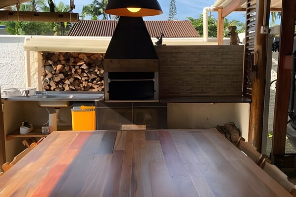 Un espacio de cocina al aire libre con un horno de leña, un lavamanos y una encimera.