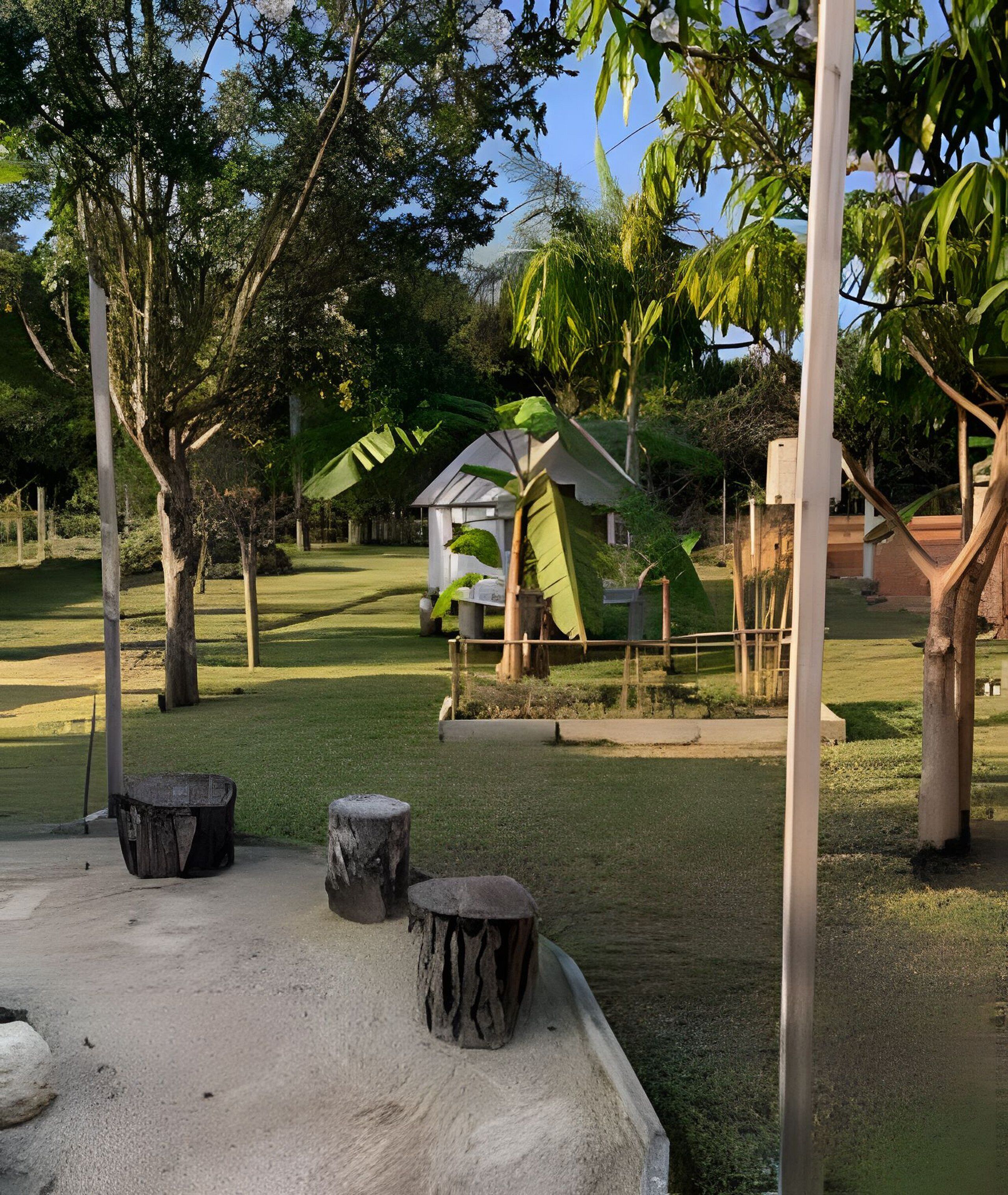 Ein Garten mit einem Pavillon, Bäumen und einer Sitzgruppe aus Beton.