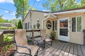 A wooden deck with two chairs and a small table, a covered porch, and a sign reading 'The Cottage.' - Wooded Cottage with Fire Pit and Boat Parking (Somerset)
