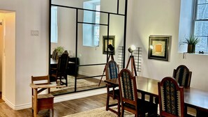 Uma sala de jantar com uma mesa de madeira, cadeiras, um tapete e um espelho grande.