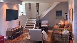 Uma sala de estar moderna com escada, TV de tela plana, sofá confortável e mesa de centro.