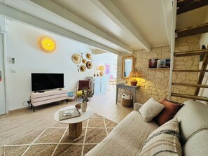 A living room with a TV, sofa, coffee table, and decorative items. - - Casa Limone - beachfront (Borgo)