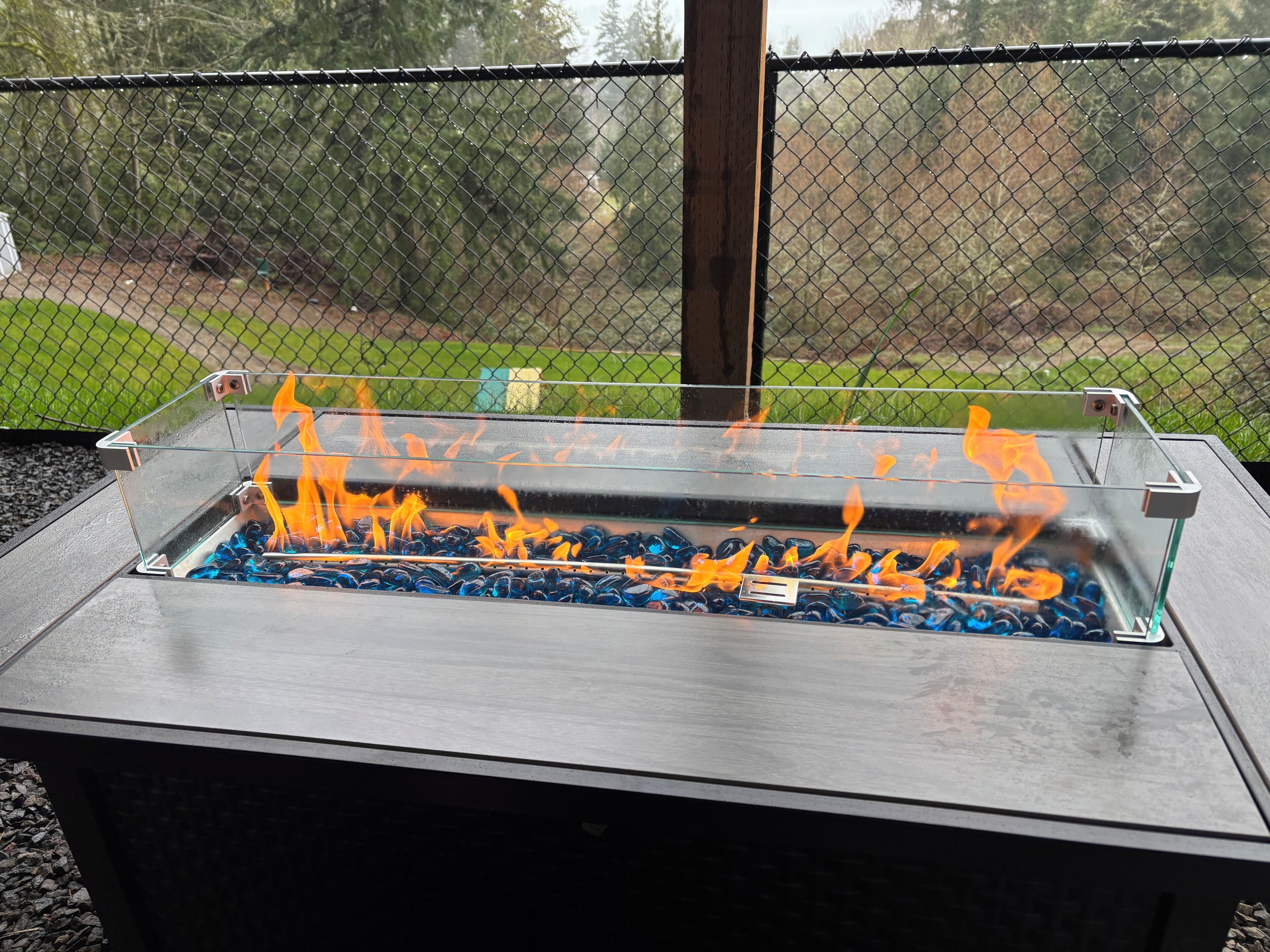 Un brasero de metal con paneles de vidrio y carbón encendido.