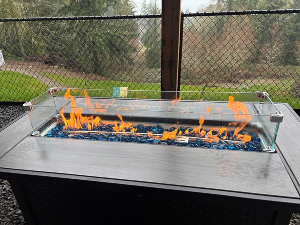 A metal fire pit with glass sides and burning charcoal.