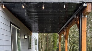 Un patio cubierto con un banco y sillas, una mesa y una estructura de pérgola.