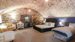A cozy room with a stone arch ceiling, a bed, a desk, and a chair. - Gatehouse Studio Apartment (Castle Douglas)