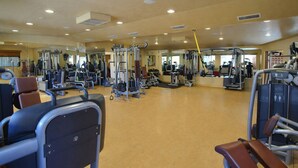 Un gimnasio amplio con diversos equipos de ejercicio, incluyendo cintas de correr, máquinas de pesas y pesas libres.