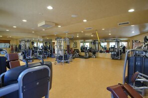 Ein geräumiges Fitnessstudio mit verschiedenen Trainingsgeräten, darunter Laufbänder, Kraftgeräte und Kurzhanteln.