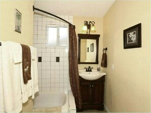 A bathroom with a bathtub, a sink, and a mirror. There is a towel rack with towels and a picture on the wall. - 55+ Resort Living with Pool, Pickleball & Spa (Mesa)