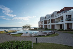 Ein modernes Gebäude mit Pool, Liegestühlen und Meerblick.