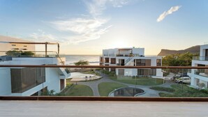 A modern building with a glass balcony overlooking a landscaped courtyard and a view of the sea. - Hacienda Iguana 3BR Corner Rooftop- Costamar (Tola)