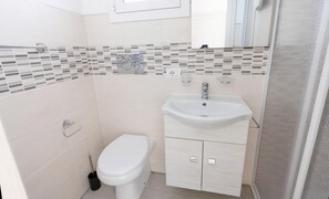 A small bathroom with a toilet, sink, and a mirror. - Appartamento Dei Tre Colli Rosa ... (Noto)