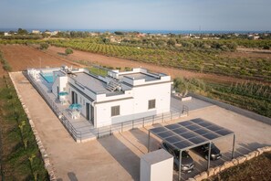 A modern building with a rooftop pool, solar panels, and a covered parking area. - Appartamento Dei Tre Colli Rosa ... (Noto)
