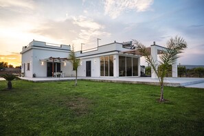 Ein modernes Haus mit geräumiger Terrasse, großen Fenstern und einem gepflegten Rasen.