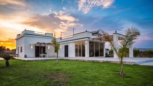 Una casa moderna con techo plano, amplios ventanales y un césped cuidado.