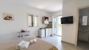 Una habitación de hotel con cama, escritorio, televisor y baño con lavabo y espejo.