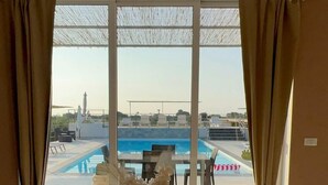 A dining area with a view of a swimming pool, a table set with a vase of flowers, and a chair. - Appartamento Dei Tre Colli Blu -... (Noto)