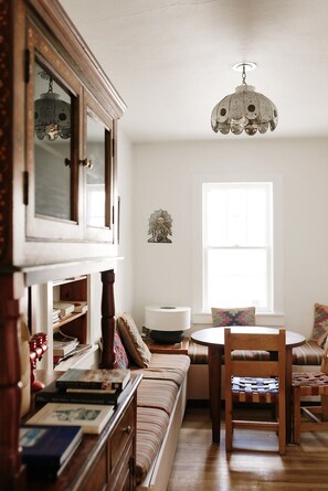 Una sala de estar acogedora con un sofá de madera, una mesa redonda y una estantería llena de libros.