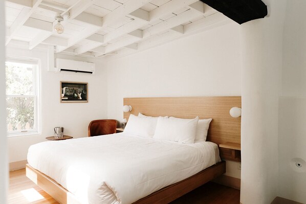 Un dormitorio amplio con una cama grande, cabecera de madera y una mesita de noche.
