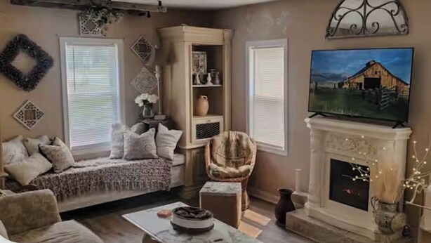 Un salon chaleureux avec une cheminée, un canapé confortable, un téléviseur et des œuvres d’art décoratives accrochées au mur.