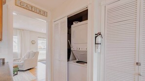 A laundry room with a washing machine and dryer, a chair, and a sign that reads "GATHER".
