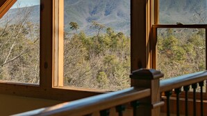 Interior de madera con vista a un paisaje montañoso a través de amplias ventanas.