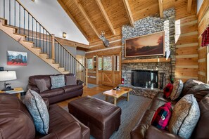 L’intérieur d’un chalet confortable, avec une cheminée, des meubles en cuir et un escalier.