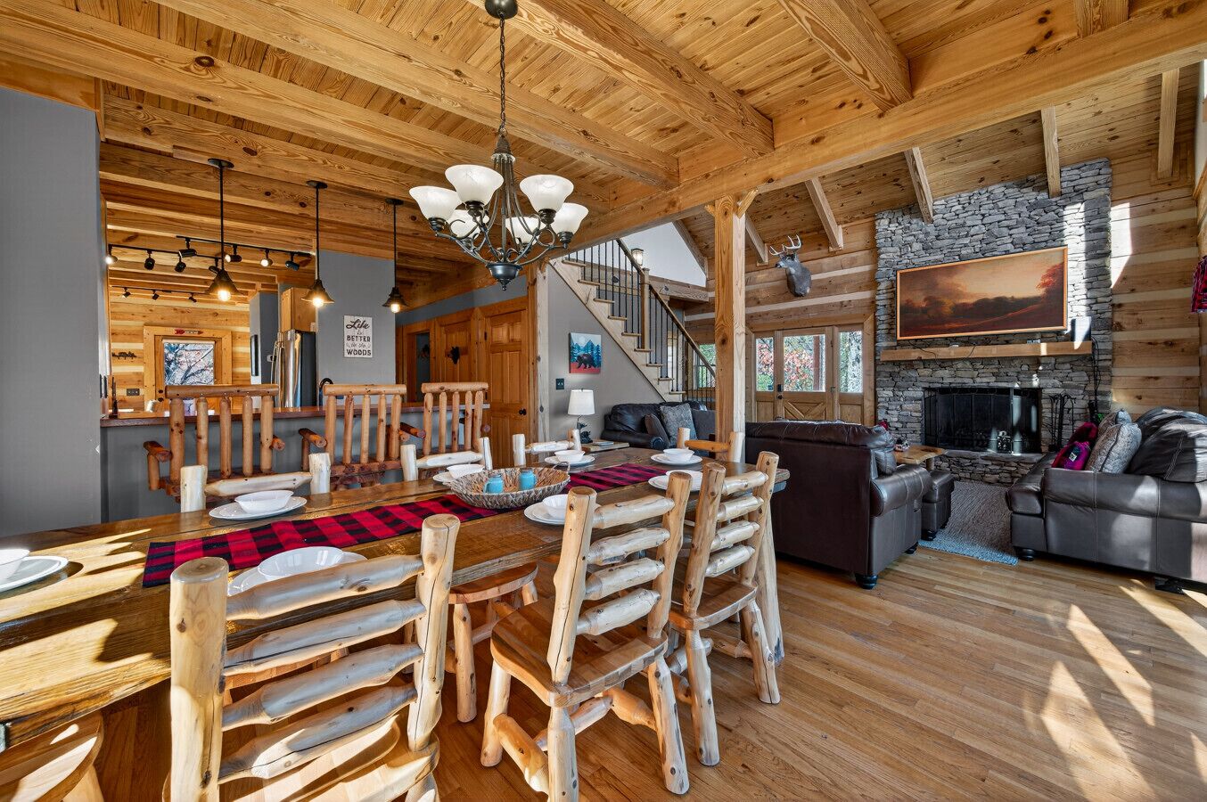A rustic wooden interior with a dining area, a fireplace, and a stone wall.