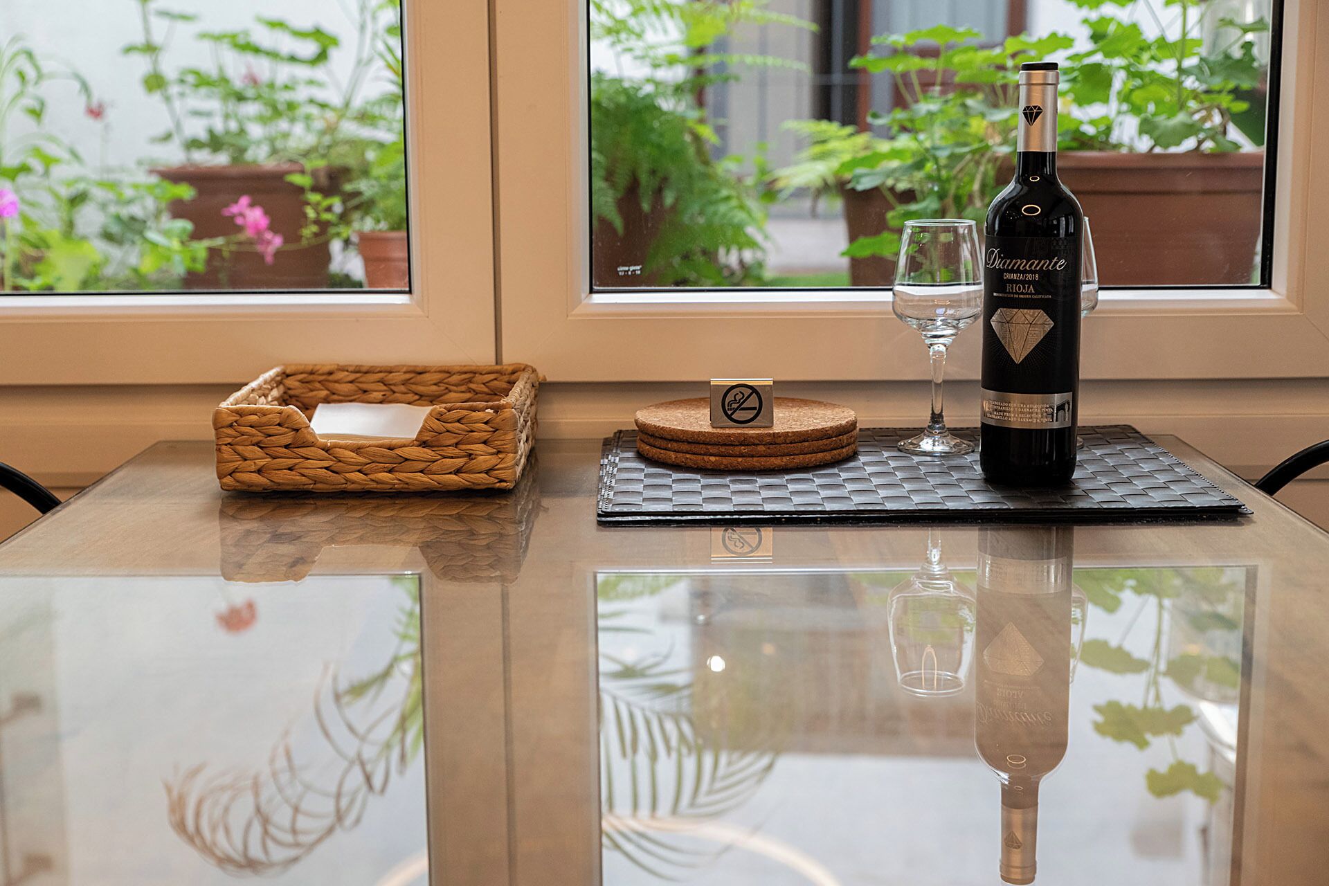 Una mesa con una botella de vino, una copa y un posavasos.