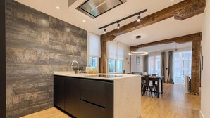 A modern kitchen with a large island, wooden beams, and a view to the dining area. - Modern and Luxurious in Historic Old Town (Bilbao)
