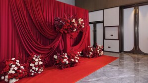 A red carpet event stage with draped curtains and floral arrangements.