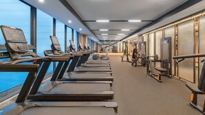 A gym with treadmills, exercise equipment, and large windows.