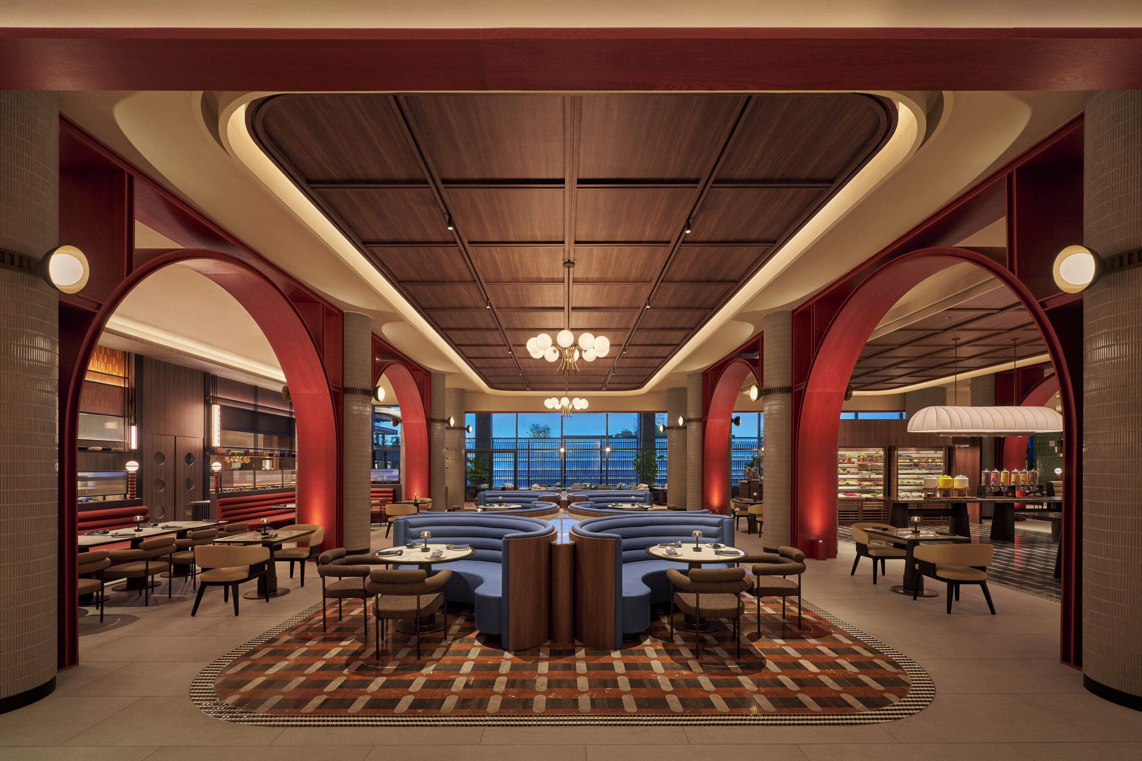 A spacious hotel lobby with a central seating area, high ceilings, and large windows.