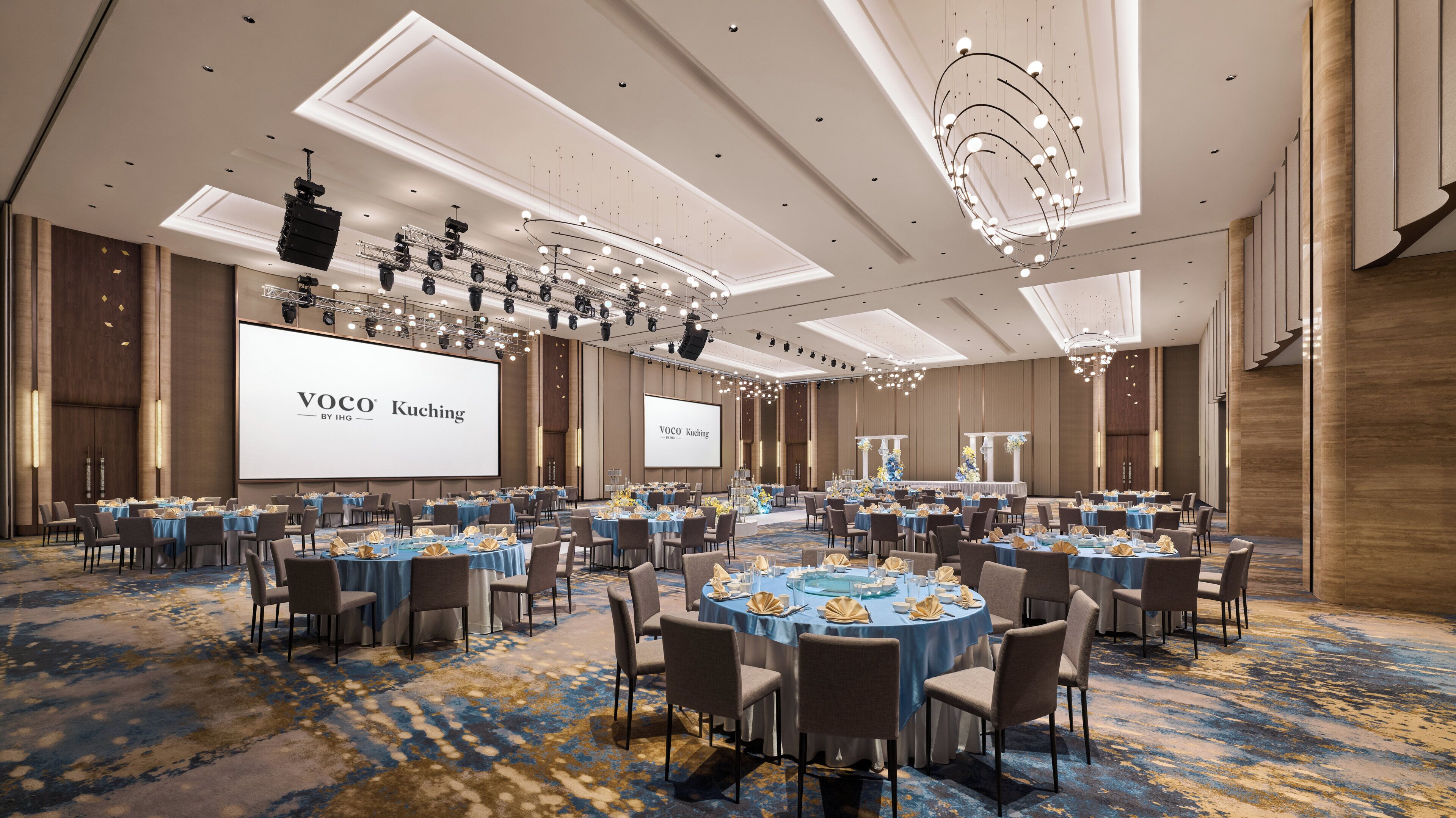 A conference room with multiple tables, a large screen, and a chandelier.