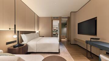 A modern hotel room with a bed, bedside table, TV, and a desk.