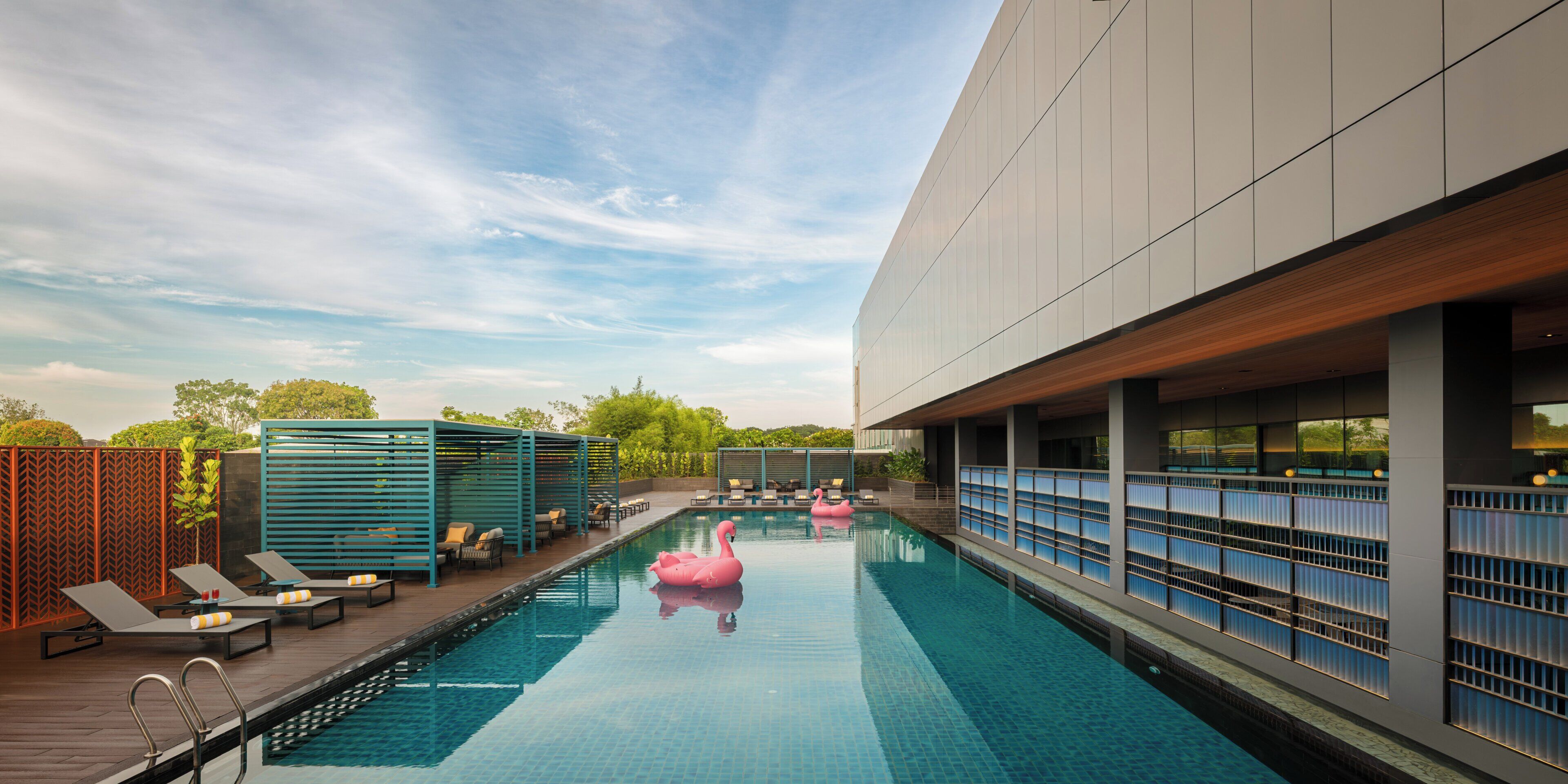 A swimming pool with lounge chairs and a pink flamingo float.