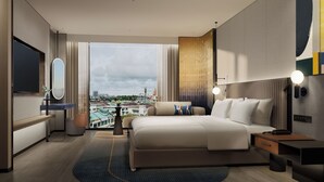 A modern hotel room with a large bed, bedside tables, a desk, and a large window offering a city view. - Voco Kuching by IHG (Kuching)