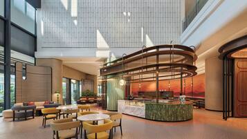 A spacious lobby with a central seating area, a circular counter, and a high ceiling with patterned wall design.
