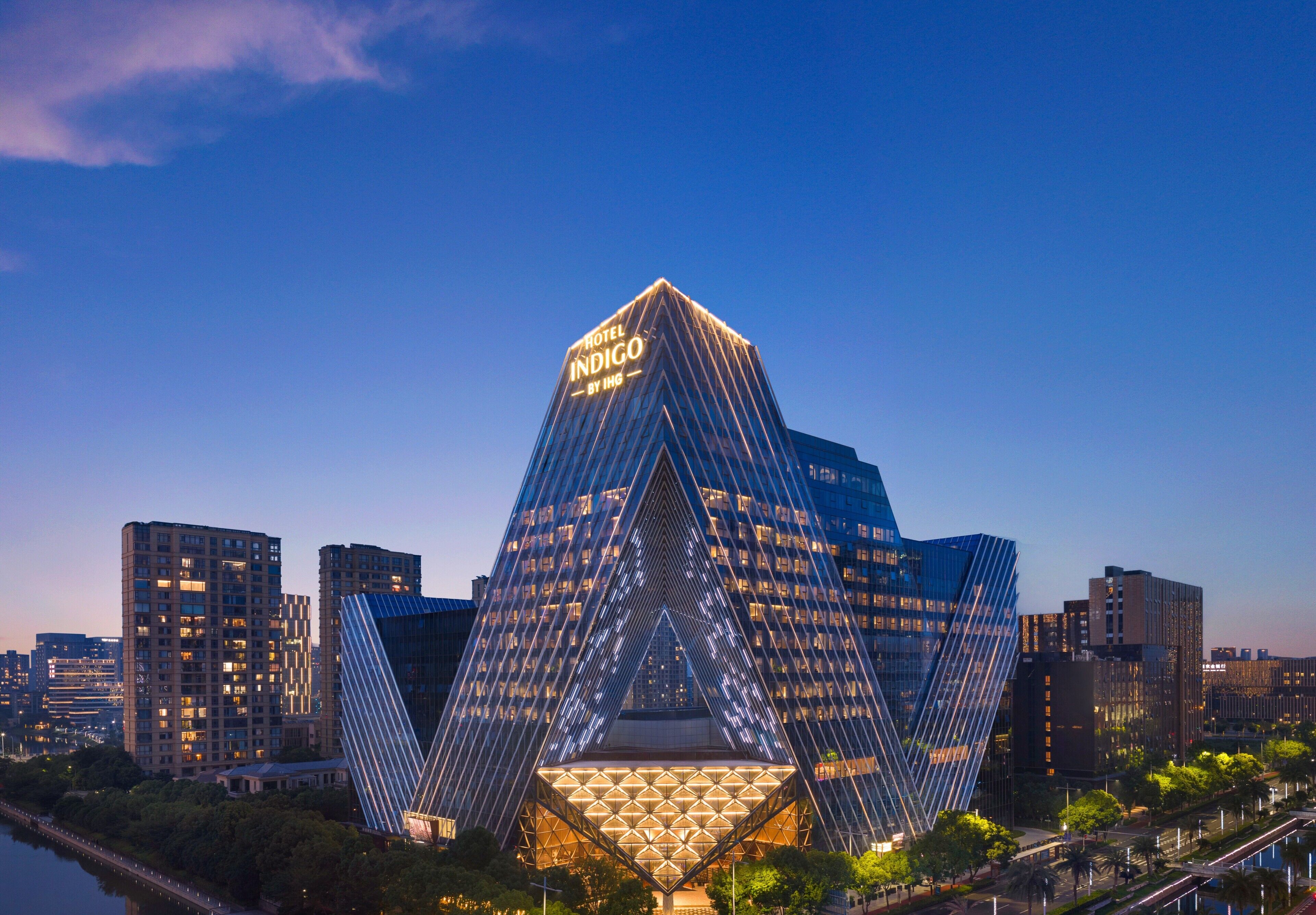 A modern hotel with a distinctive triangular glass facade and a prominent sign at the top.