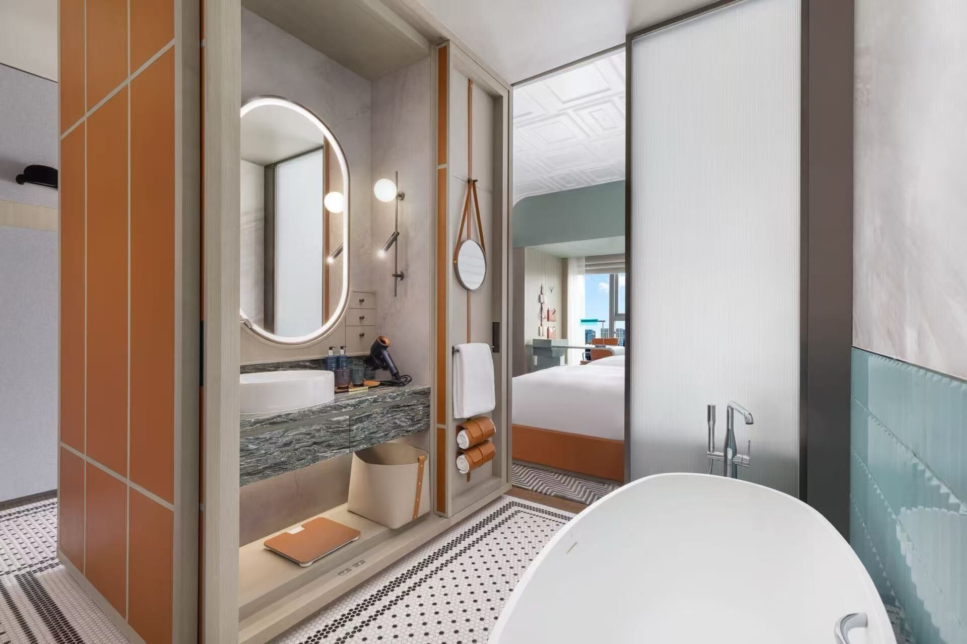 Een moderne badkamer met een marmeren wastafel, een grote spiegel, een ronde lamp, een badkuip en een douche.