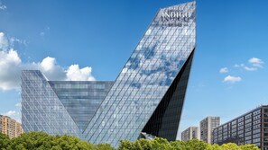 A modern hotel with a distinctive angular glass facade, named 'Hotel Indigo by the HG.' - Hotel Indigo Ningbo By Ihg (Ningbo)