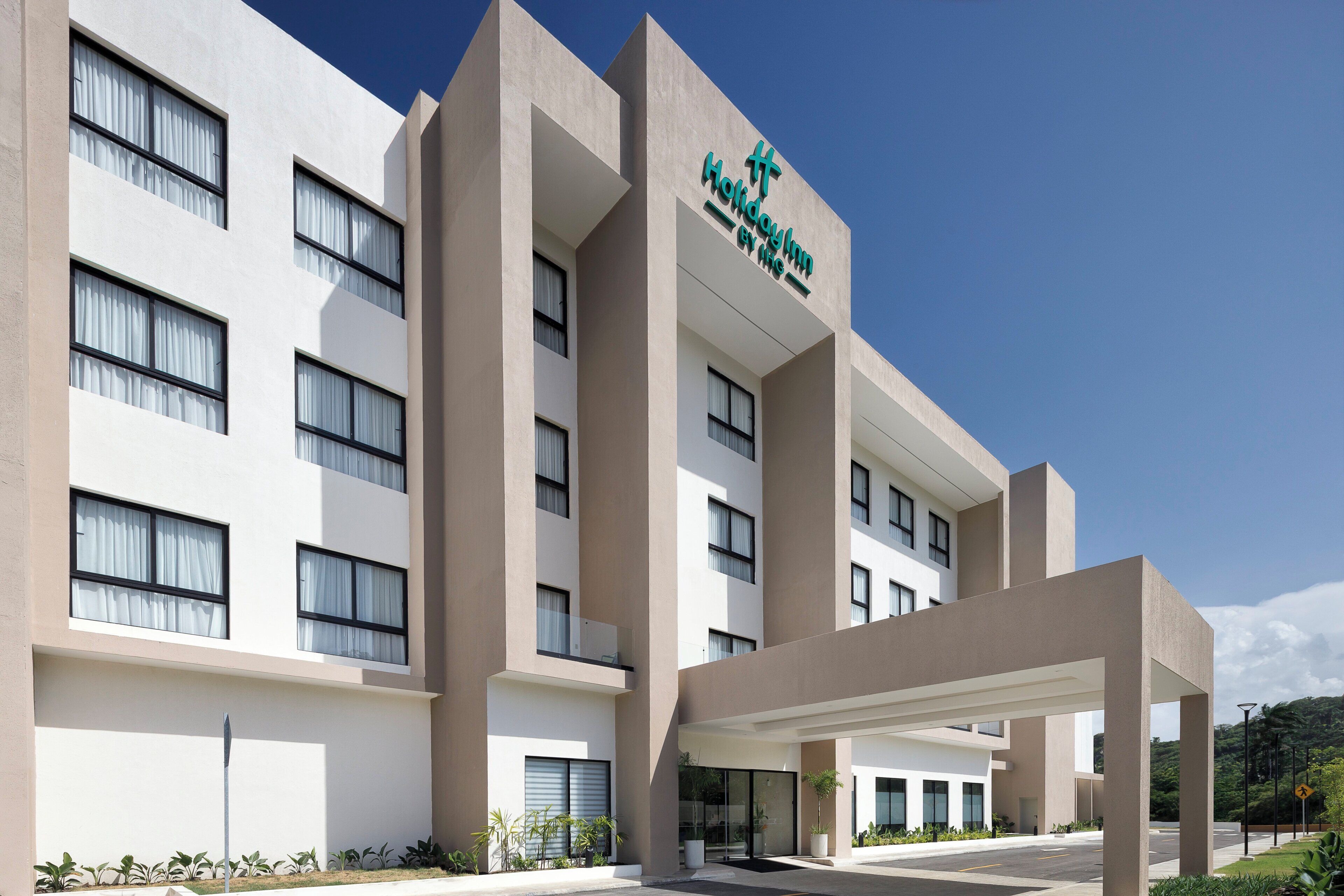 Un bâtiment d’hôtel moderne, doté d’une enseigne bien visible, de nombreuses fenêtres et d’un espace d’entrée abrité.