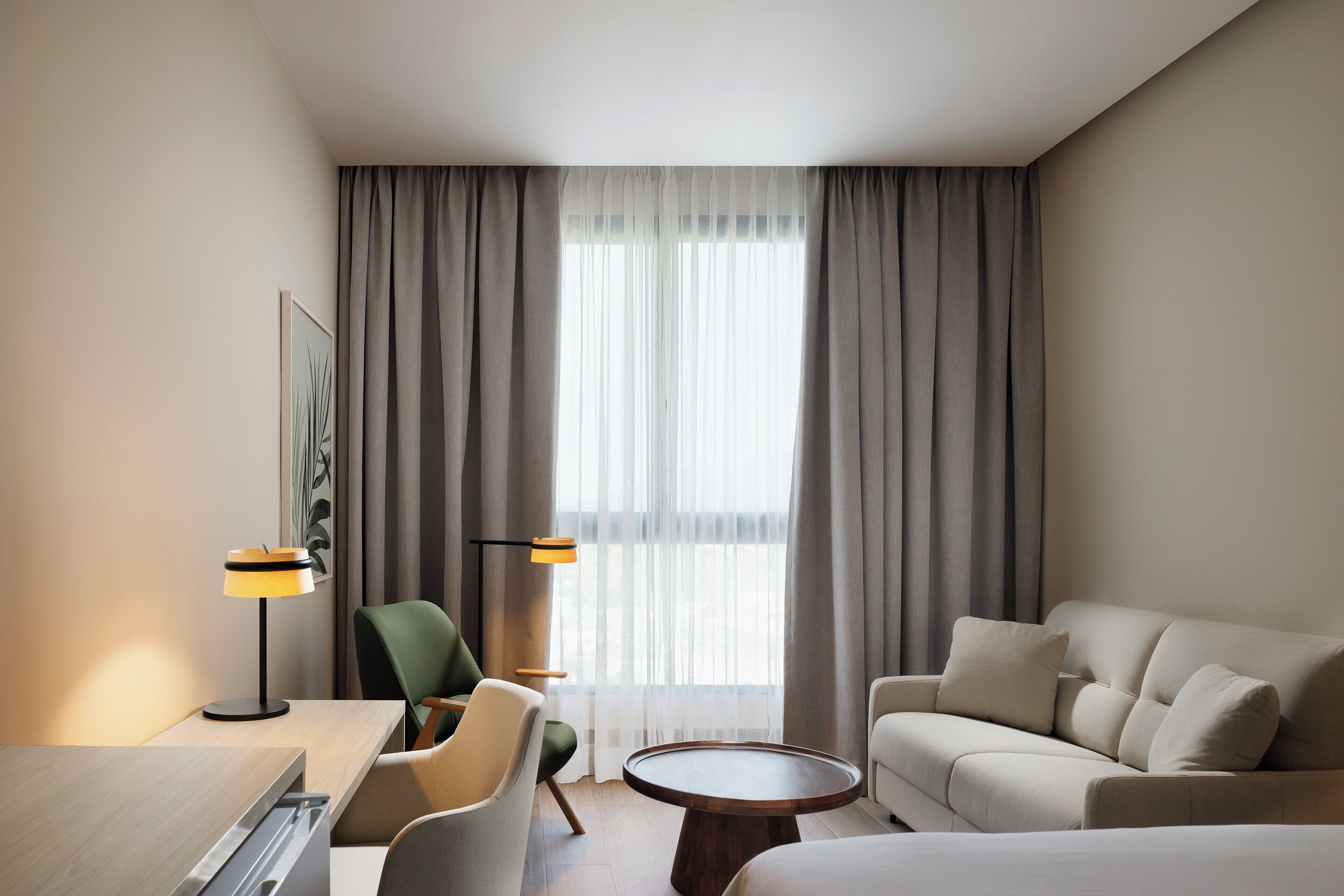 Une chambre d’hôtel comprenant un lit, un canapé, un bureau, une chaise et une table ronde.