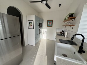 A modern kitchen with a stainless steel refrigerator, a white sink with a black faucet, and a ceiling fan. - Historic Charm, Modern Style: Private 2Bed Cottage with amazing country views (Hopewell)