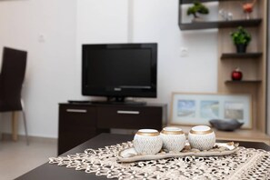 Ein Esstisch mit einer verzierten Tischdecke, drei weiße Keramiktassen mit Goldakzenten und einer Serviertschale.