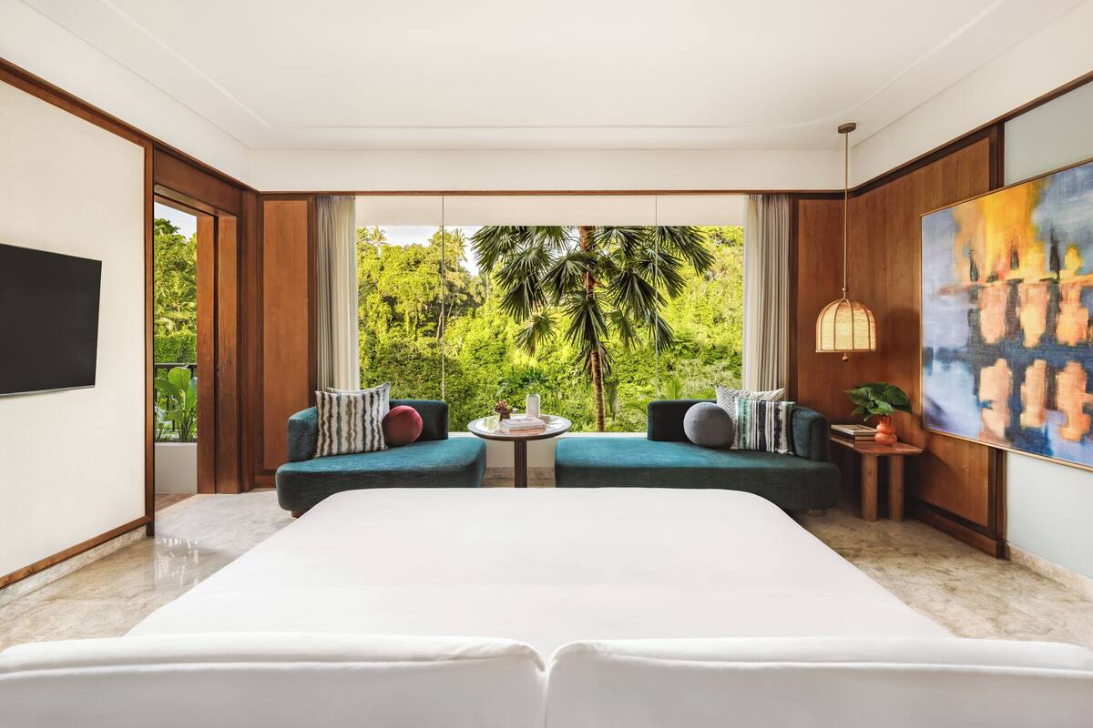 Une chambre d’hôtel moderne avec un grand lit, deux canapés, une télévision et un tableau.
