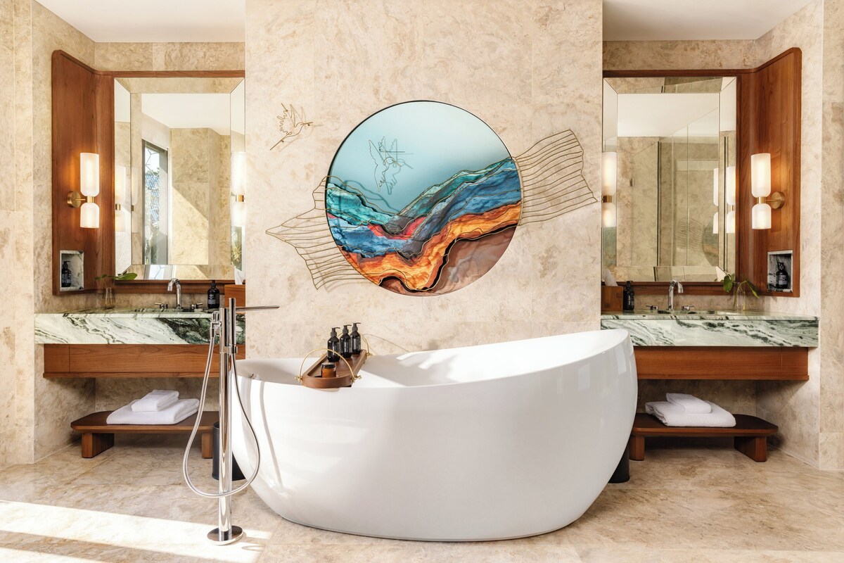 Ein modernes Badezimmer mit einem großen, ovalen Waschbecken, Marmorplatten und einem wandmontierten Spiegel.